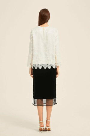 Rear view of ivory jacquard blouse with lace hem paired with a black midi skirt — elegant day-to-evening combination by Sioéne.