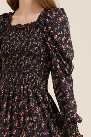 Close-up of the smocked bodice and puff sleeve detail on a black floral maxi dress, highlighting the gathered texture and delicate rose print.