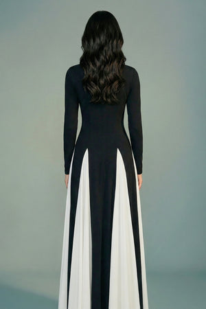 The model is shown from the back wearing a black long-sleeve maxi dress with ivory panel inserts, revealing a clean back line and graceful skirt flow.