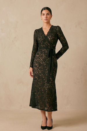 Model stands slightly angled wearing a black lace wrap midi dress with a flattering V neckline, sheer lace sleeves, and a wrap silhouette that contours the waist.