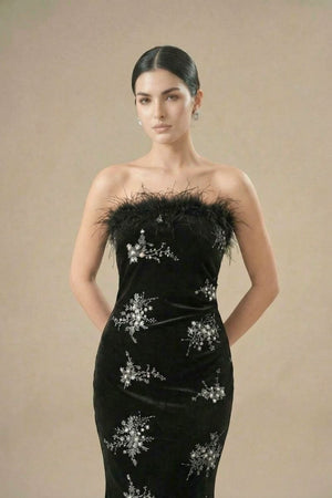 Close-up of a black velvet gown featuring a feather-trim strapless neckline and silver floral embroidery.