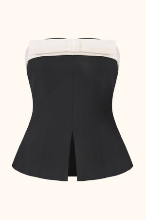 A black strapless top with a white bow trim shown from the back, highlighting its structured shape and center back slit.
