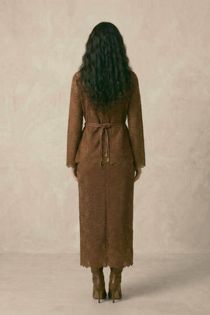 A woman shown from the back wearing a brown lace long-sleeve top and matching lace midi skirt, finished with a braided belt tied at the waist.