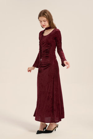 Model in motion wearing burgundy velvet maxi dress with gentle sheen, long sleeves, and subtle waist ruching, elegant and feminine.