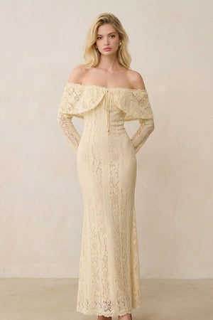 Front view of a buttercream lace off-shoulder maxi dress featuring a fitted bodice, scalloped lace overlay, and refined long sleeves, styled in a minimalist studio setting.