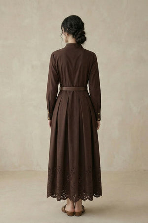 A woman shown from the back wearing a coffee brown long-sleeve shirt midi dress with structured pleats, a belted waist, and a scalloped eyelet hem.