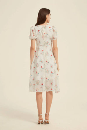 Back view of a cream floral midi dress showing fitted waist and flowy skirt — elegant puff-sleeve design perfect for countryside or vacation days.