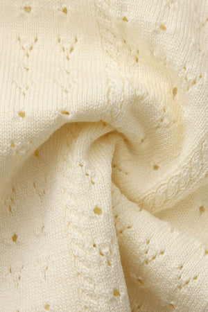 Close-up image of cream pointelle knit fabric showing its delicate openwork pattern, soft yarn texture, and detailed stitching for a cozy, lightweight feel.
