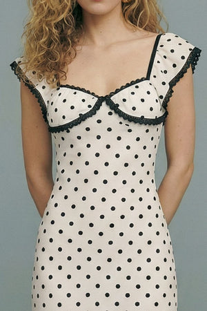 Close-up of the cream polka dot midi dress highlighting the structured bust, black lace trim, and delicate flutter sleeves on the model.