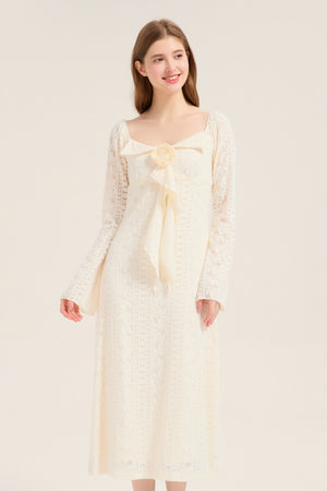 Model smiling in an ivory lace long sleeve midi dress featuring a romantic bow and rose detail, perfect for bridal or garden occasions.