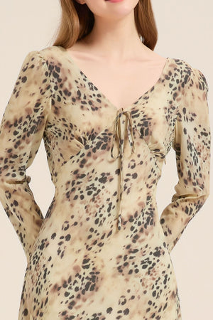 Close-up of leopard print satin dress showing tie-front neckline and smooth drape in soft beige and brown tones.