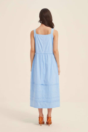 Back view of a woman wearing a light blue sleeveless midi dress with lace-trim straps and a gathered waist, crafted from soft lightweight cotton fabric.