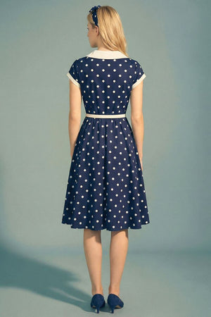 Back view of a navy polka dot midi dress with a contrast ivory collar and defined waist, highlighting the clean back construction and softly flared skirt.