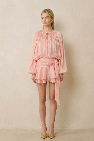 Full front view of the peach chiffon blouson top and matching ruffled shorts, showing a relaxed drape, cinched waist tie, and fluid layered hem.