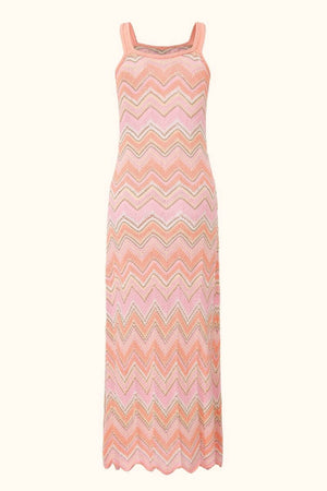 The back view of a peach-pink chevron knit maxi dress showing the same textured zigzag knit pattern and long straight hem with a scalloped edge.