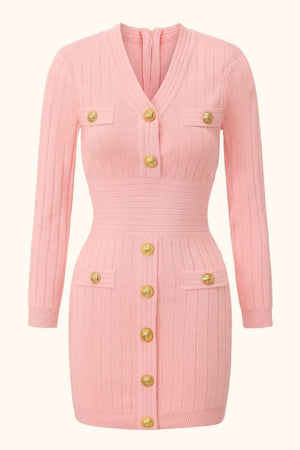 Front view of a pink ribbed knit mini dress with long sleeves, gold buttons, v-neckline, and bodycon silhouette, elegant feminine knitwear.