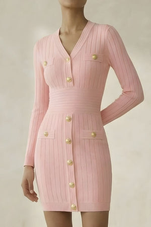 Model wearing a pink ribbed knit mini dress with long sleeves, gold statement buttons, and a fitted waist, photographed against a neutral backdrop.