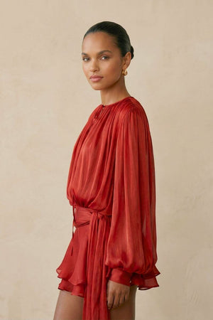 Side view of the red chiffon mini dress showcasing the lightweight sheer sleeves, softly cinched waist sash, and flowing layered hem that moves effortlessly.