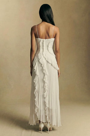 Back view of a white pleated halter midi dress featuring slim straps, a softly ruched back bodice, and cascading ruffle details down the skirt.