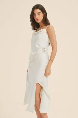 Side view of a white satin midi dress showing the soft drape, floral details, and subtle slit, styled for an elegant evening look.
