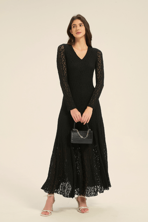 Black lace long sleeve maxi dress styled with a small black handbag and white strappy heels.