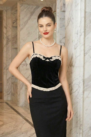 Model in a black velvet lace-trim corset and pearls posing inside a marble hallway, showcasing an elegant vintage-inspired evening look.