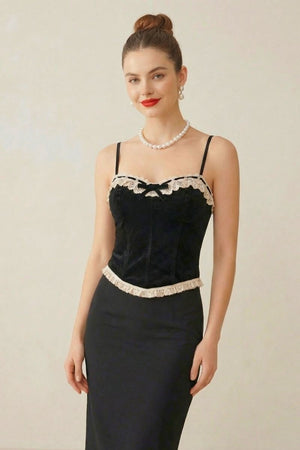 Close-up view of a model in a black velvet lace corset top with cream lace details, styled with pearl jewelry and red lipstick.