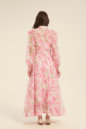 Back view of pink floral maxi dress with soft pleats, waist tie, and full-length flowing skirt.