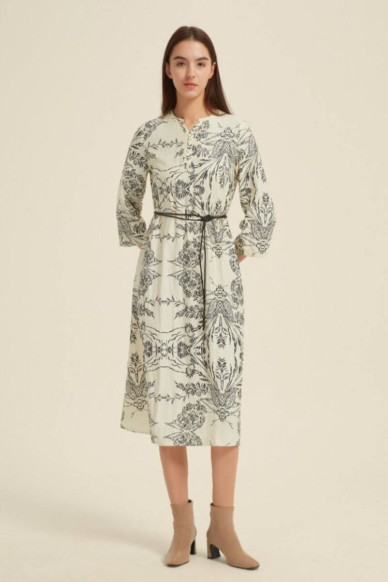 Angled front studio shot of a cream, floral-print midi dress featuring a notch neckline, 3/4 sleeves, and a thin waist tie.