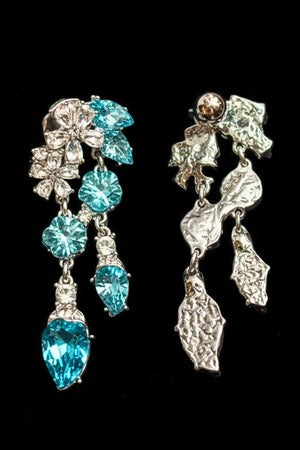 The reverse side of aqua crystal leaf drop earrings, revealing the textured silver-tone metal backing and articulated drop structure against a black background.