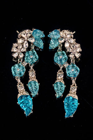 A pair of aqua blue crystal drop earrings with leaf-shaped stones and clear crystal accents, arranged symmetrically on a black reflective surface.