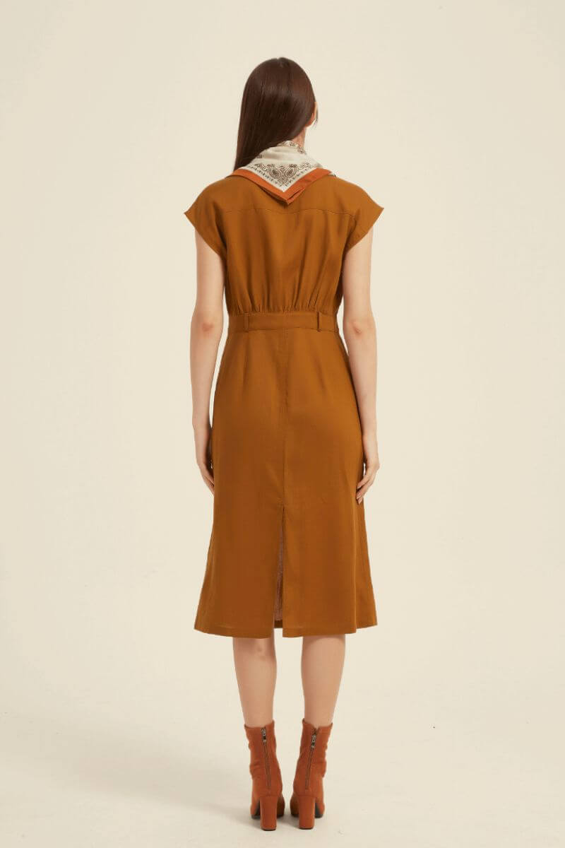 Rear view of a rust-colored midi shirt dress with elastic waist and soft drape, styled with a printed scarf for an elegant back-detail look.