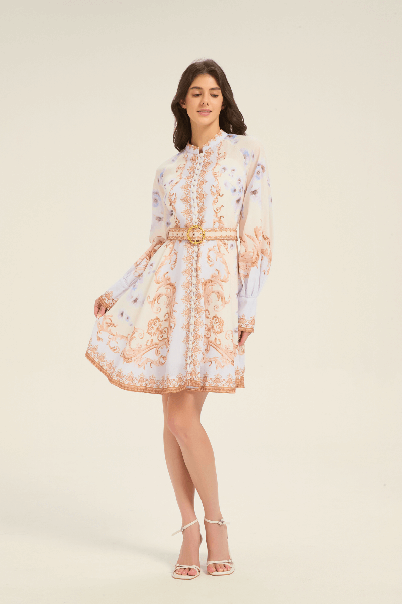 Full-body front view of cream mini dress with baroque gold scroll design and blue floral accents, long puff sleeves, and belted waist.