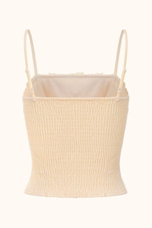 Back view of a beige satin corset top featuring smocked elastic paneling, slim adjustable straps, and soft lace-edged hem on white background.