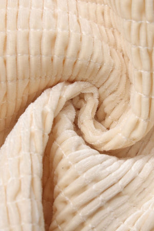 Close-up photo of soft beige velvet smocked fabric showing raised ribbed texture and plush sheen, used for Sioéne corset tops.