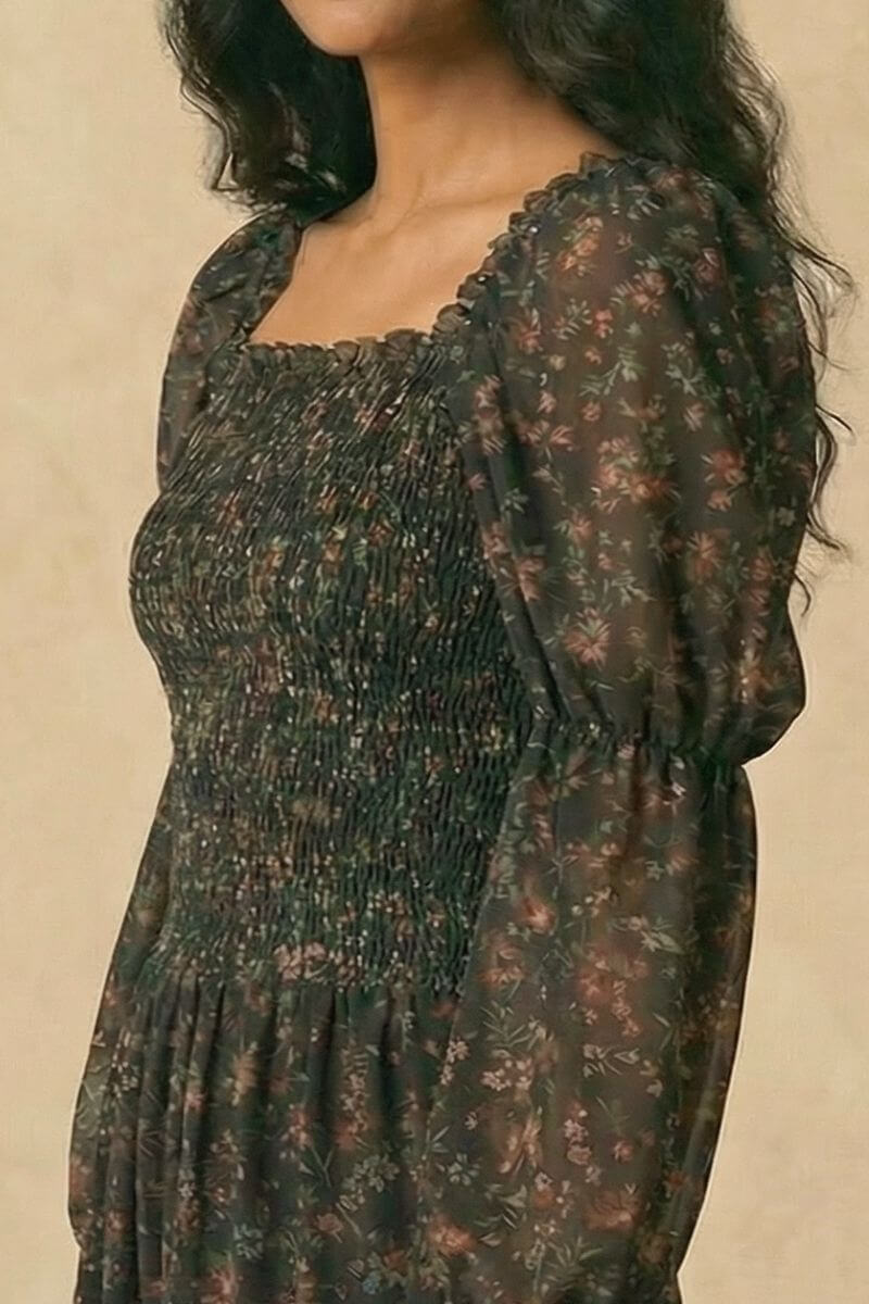 Close-up view of the black floral midi dress showing the smocked bodice, sheer puff sleeves, and square neckline with delicate ditsy florals.