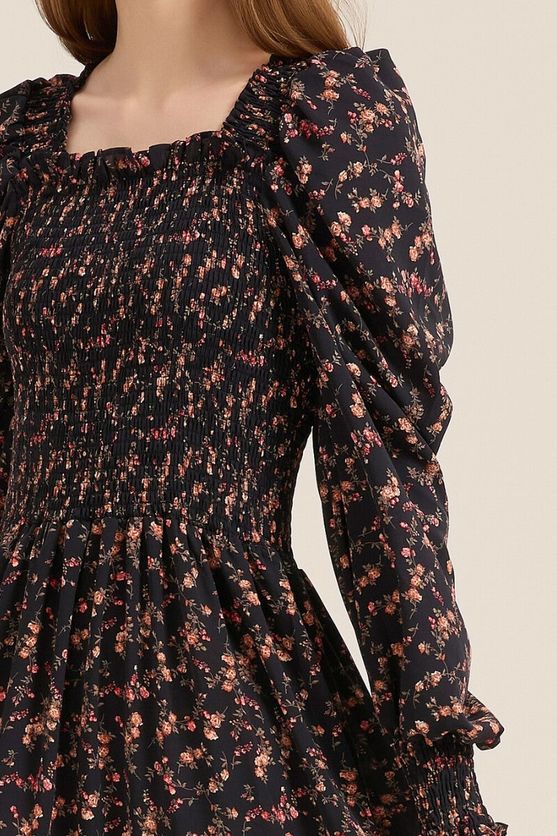 Close-up of the smocked bodice and puff sleeve detail on a black floral maxi dress, highlighting the gathered texture and delicate rose print.