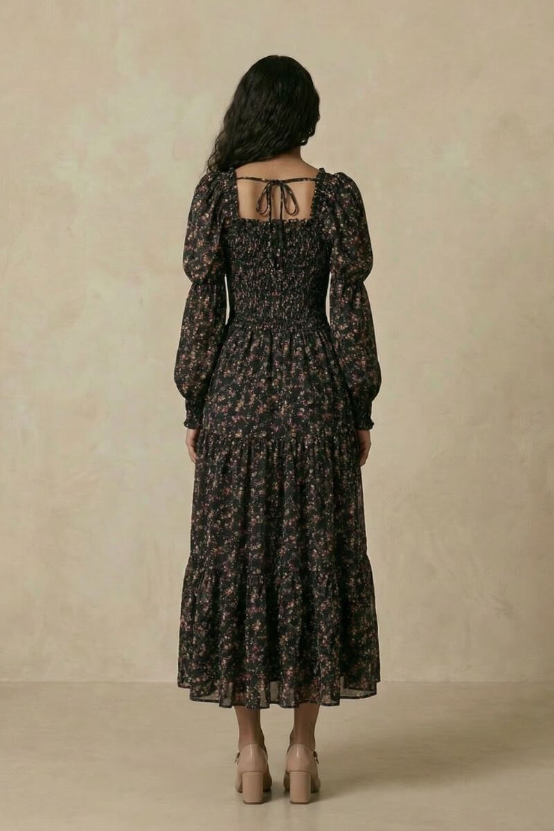Back view of the black floral smocked midi dress highlighting the tie-back square neckline, puff sleeves, smocked waist, and tiered midi-length skirt.