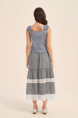 Back view of a black gingham sleeveless top and tiered lace-trim skirt, highlighting the fitted bodice and ruffled shoulder design.
