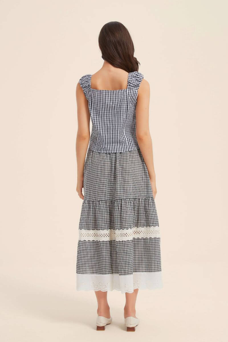 Back view of a black gingham sleeveless top and tiered lace-trim skirt, highlighting the fitted bodice and ruffled shoulder design.