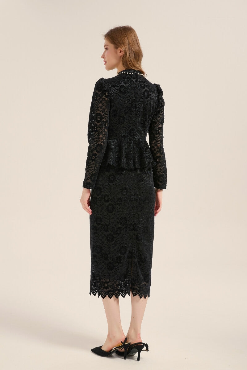 Back view of a black lace peplum midi dress with long sleeves, scalloped hemline, and subtle slit detail, paired with black slingback heels for a refined finish.
