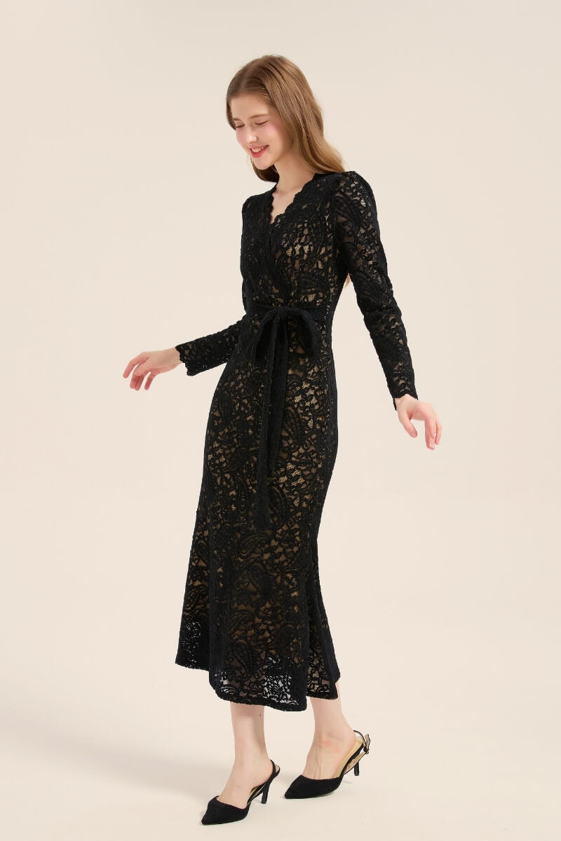 Model turning sideways in a black lace midi dress with intricate floral lace overlay and belted waist for a flattering silhouette.