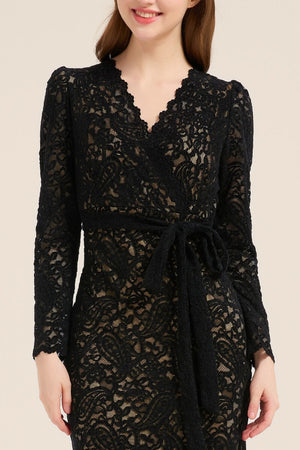 Close-up of a black lace wrap dress with scalloped neckline and waist tie detail, highlighting the delicate floral lace pattern.