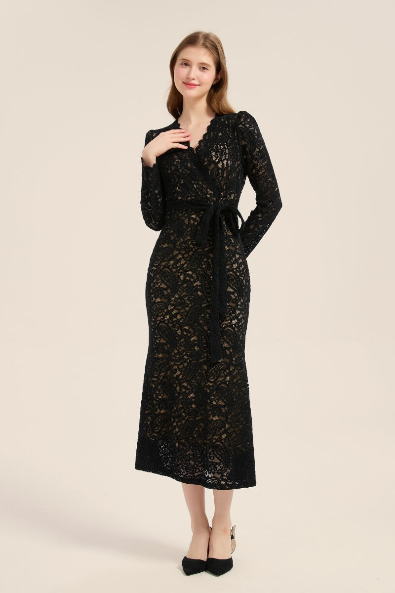 A woman in a fitted black lace wrap dress showing scalloped V-neck and waist tie detail, highlighting elegant sheer lace texture.