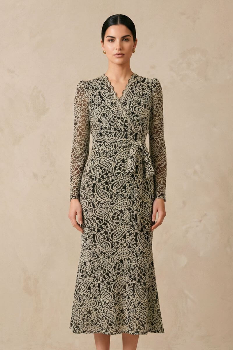 Front view of a model in a black lace wrap midi dress featuring sheer long sleeves, a feminine V neckline, and an elegant mid-calf length silhouette.