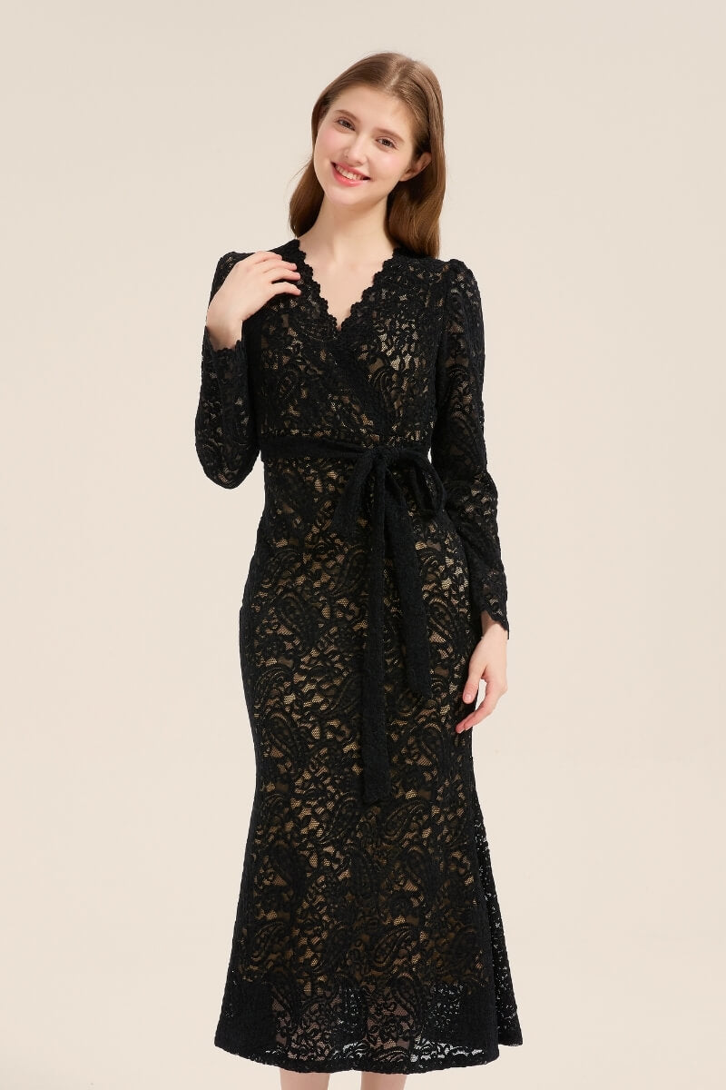 Model wearing a black lace wrap midi dress with long sleeves, scalloped neckline, and self-tie waist belt, styled with black slingback heels.