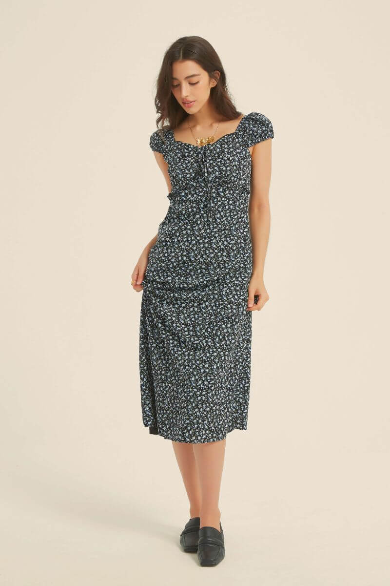 Front view of black micro-floral midi dress with cap sleeves, ruffle trim, and tie-front waist