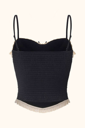 Back view of a black velvet corset top with stretchy smocked panel, adjustable thin straps, and cream lace edging, displayed on a white background for Sioéne.