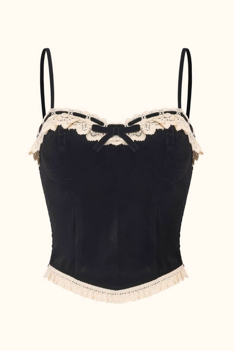 Front view of a black velvet corset top featuring thin straps, cream lace trim, and a small velvet bow, photographed on a white background for Sioéne.