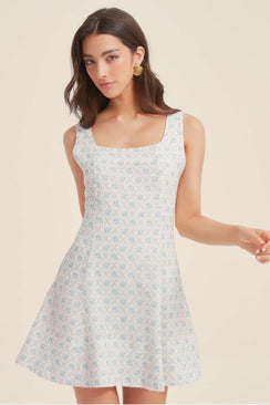 Close-up of the blue jacquard floral mini dress showing the textured floral pattern, square neckline, and soft pastel detailing.